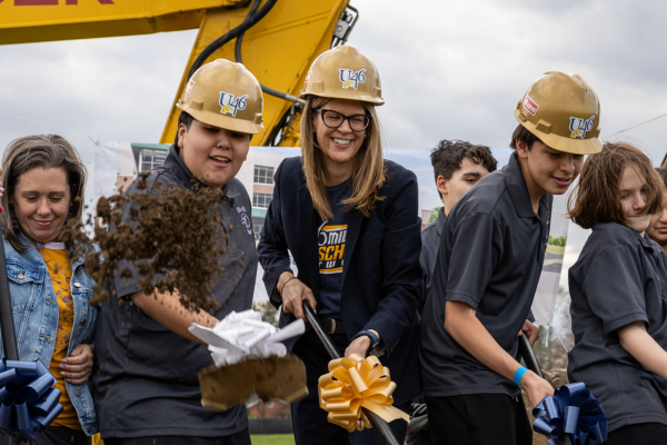 Two boys and a woman in glasses dig with a shovel
